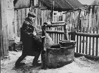 a member of the Kovno ghetto underground hides supplies in a well used as the entrance to a hiding place in the ghetto. Kovno, Lithuania, 1942